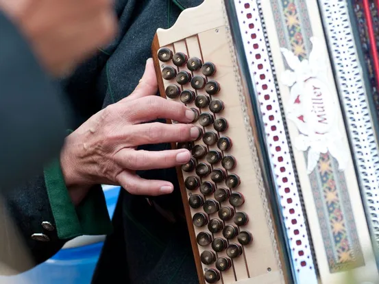 Hand spielt Knöpfe auf einem traditionellen diatonischen Akkordeon mit Verzierung